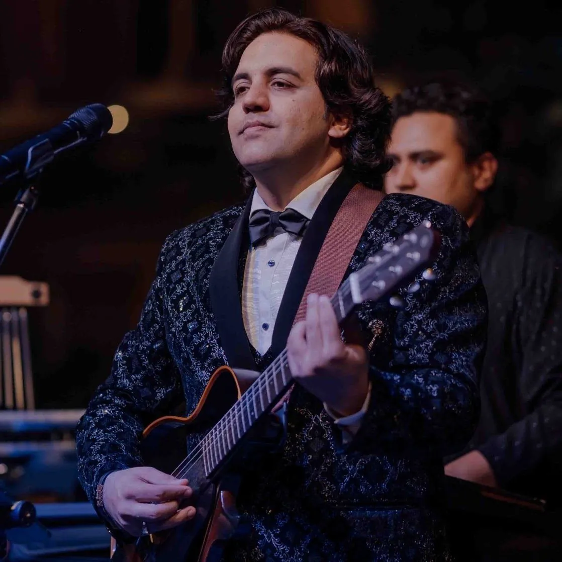 Ankit Batra in a black tuxedo, singing with his guitar
